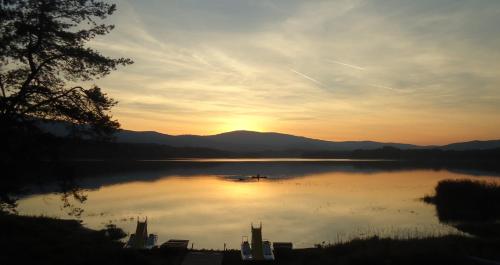 a sunset on a lake with a boat in the water at Camping u Kukačků in Horní Planá