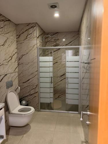 a bathroom with a toilet and a glass shower at Ocean Breeze Apartment in Maputo