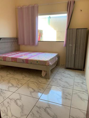 a bedroom with a bed and a window and a tiled floor at Casa Camocim Marilago in Camocim