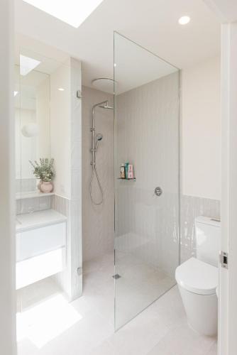 a white bathroom with a shower and a toilet at Splendid Spacious - Port Melbourne Beachside Home in Melbourne
