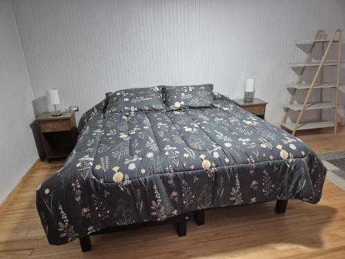 a bedroom with a bed with a black comforter at Alojamiento Costanera in Laraquete