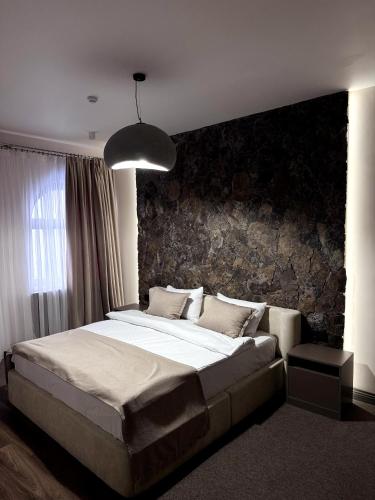 a bedroom with a large bed with a stone wall at Château Byurakan Hotel in Byurakan