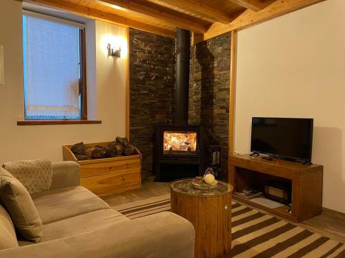 a living room with a couch and a tv and a fireplace at Casa de Xisto Ti Maria in Videmonte