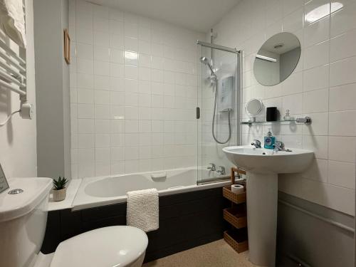a bathroom with a sink and a toilet and a tub at 2 Nookdales Cottages in Ingleton
