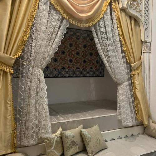 a bedroom with a bed with curtains and pillows at Dar EMNA in Kairouan
