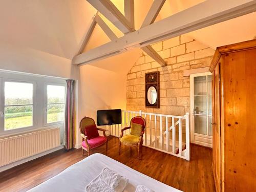a bedroom with two chairs and a table and a tv at Logis Hotel Demeure de la Vignole in Turquant