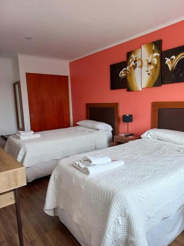 two beds in a hotel room with red walls at Hotel Americano in Perito Moreno