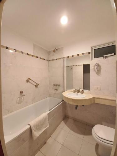 a bathroom with a tub and a sink and a toilet at Hotel Americano in Perito Moreno