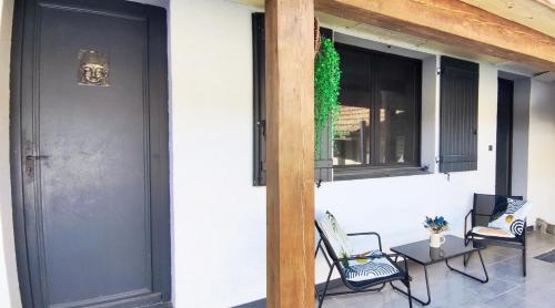 a porch with chairs and a black door and windows at Studio en campagne in Retournac