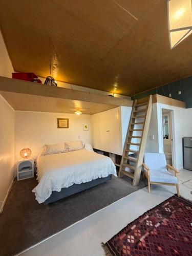 a small bedroom with a bed and a staircase at Self-contained studio by the beach in Paekakariki