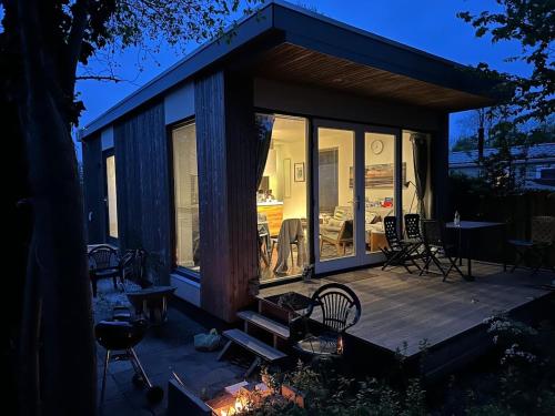 a small cabin with a deck with a table and chairs at Litehomeatseagoedereede in Goedereede