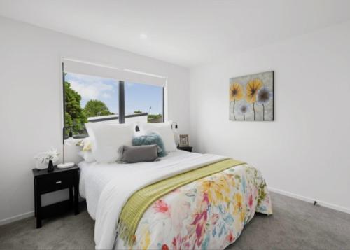 a white bedroom with a large bed and a window at Unique Stays in Auckland