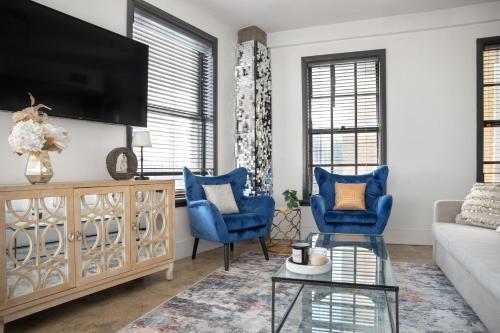 a living room with blue chairs and a tv at Stylish loft 2 queens & 2 sofas in Los Angeles