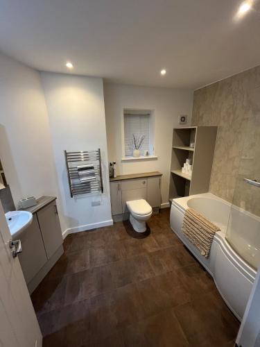 a bathroom with a tub and a toilet and a sink at An Treth in Bude