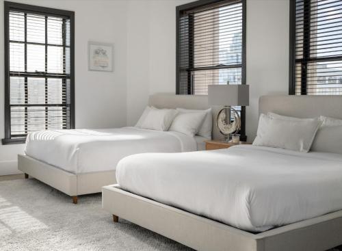 two beds in a white room with windows at Bright lights central Downtown in Los Angeles
