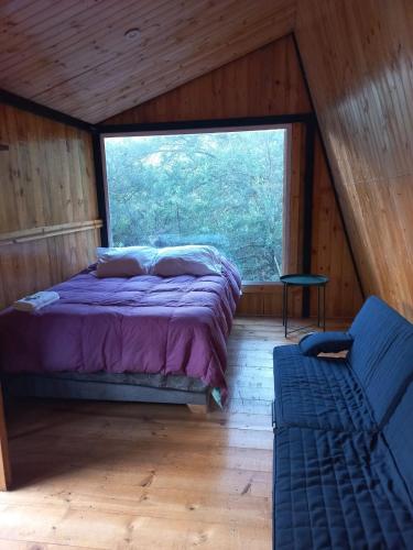 a bed in a room with a large window at Bosque Venado de Oro in Guatavita