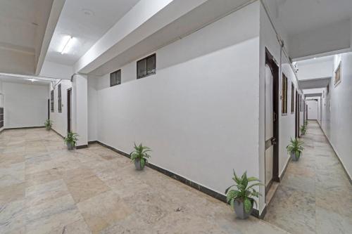 a hallway with potted plants in a building at Hotel O Grand Pallavaram in Chennai