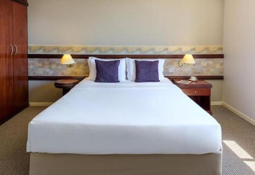 a bedroom with a large white bed with purple pillows at Prinz Loft in Joinville