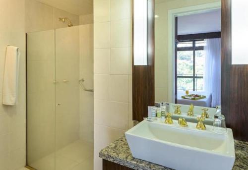 a white bathroom with a sink and a shower at Prinz Loft in Joinville
