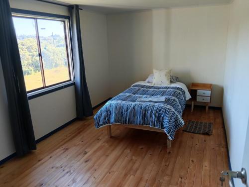 a bedroom with a bed and a large window at Lomas de Hullinco Lodge in Petanesí Alto