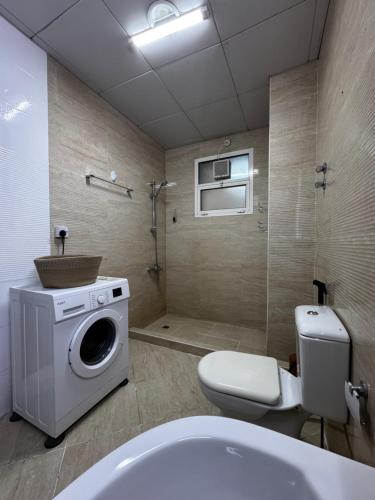 a bathroom with a washing machine and a toilet at Modern Style Designer Studio Apartment in Abu Dhabi