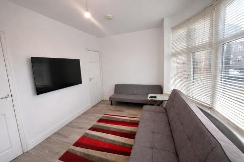 a living room with a couch and a flat screen tv at Cozy 1-Bed Flat Ideal for Short & Long Stays in Manchester