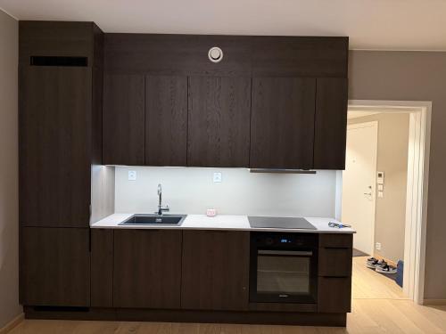 a kitchen with dark brown cabinets and a sink at Oslo Gateway Apartment in Lørenskog in Lorenskog
