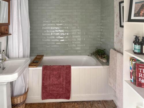 a bathroom with a bath tub and a sink at Hill House in Colchester
