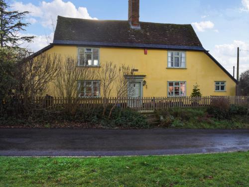 a yellow house with a fence in front of it at Hill House in Colchester