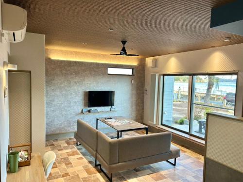 a living room with a couch and a tv at East Villa Shimanami Mukaishima seafront in Onomichi