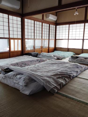 a room with four beds in it with windows at T&T Fujiyama SAKURA in Fujiyoshida