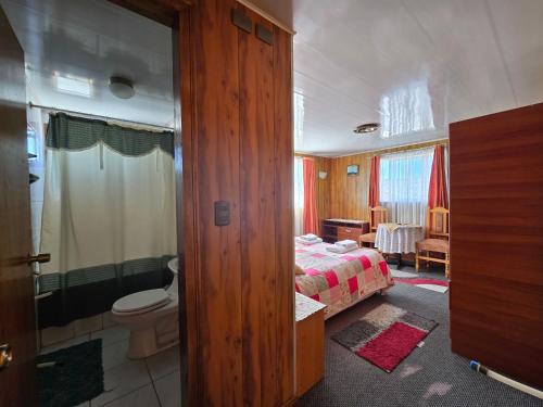 a bedroom with a bed and a bathroom with a toilet at Hotel Bahia in Quellón
