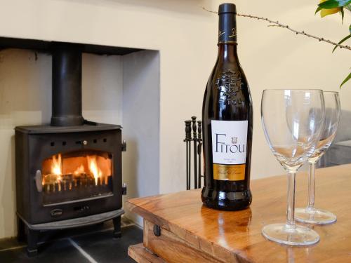 a bottle of wine and a glass on a table with a stove at Gilbert's Warrant in Keswick