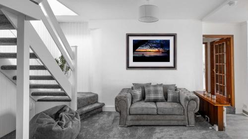 a living room with a couch and a staircase at Craigend Cottage in Rothesay