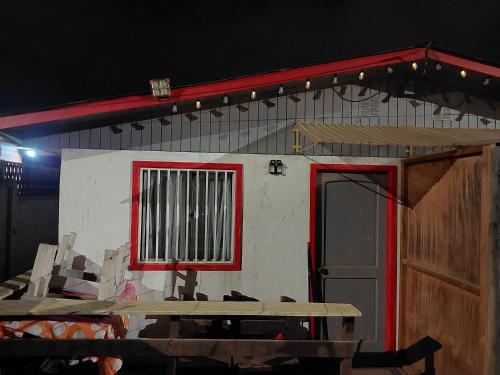 a small house with a red window and a table at Happy Valley in Isla Negra