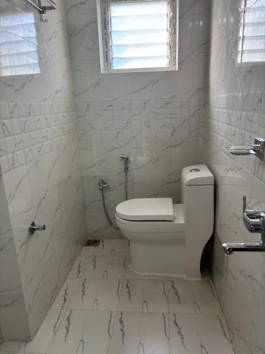 a white bathroom with a toilet and a window at Janaa Residence in Dithur