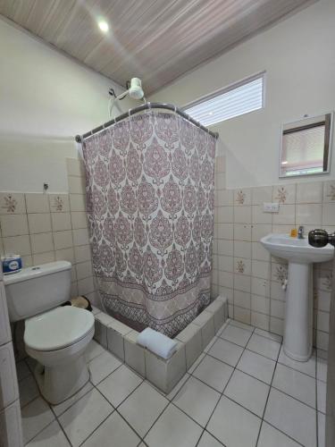 a bathroom with a toilet and a shower curtain at Hotel Don Fito in Golfito