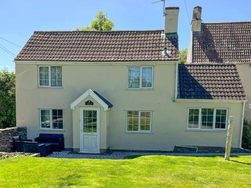 a white house with a white door and a yard at Commonwealth Cottage in Iron Acton