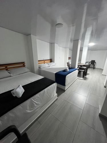 a bedroom with two beds and a table and chairs at Hotel ZT in Mariquita