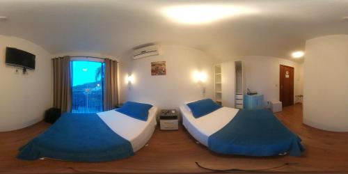 a bedroom with two beds and a large window at The Hyperion Boutique Hotel in Florianópolis