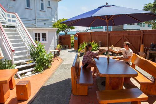 two women sitting at a table with an umbrella at Moana Lodge in Plimmerton