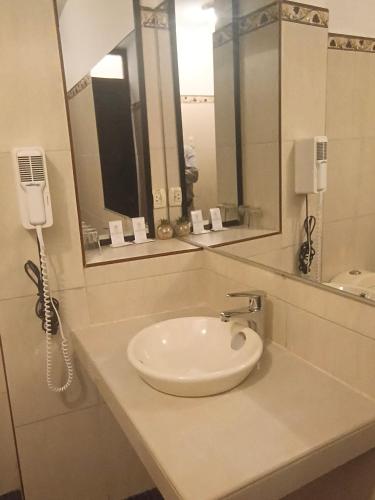 a bathroom with a sink with a phone and a mirror at Colonial Plaza Hotel in Puno