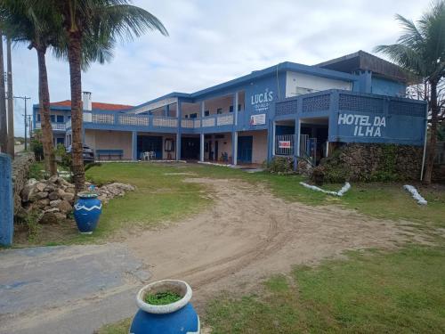 a large building with palm trees in front of it at Pousada hotel da ilha lounge Beach Lucas do Gelo in Ilha Comprida