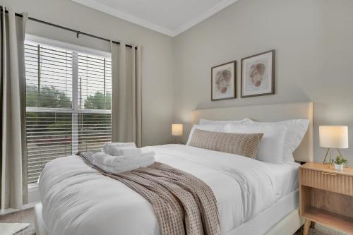 a white bedroom with a large bed and a window at Sapphire 1BD Loft - Pool, Gym & Free Parking! in Dallas