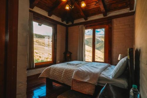 a bedroom with a bed in a room with two windows at Solarium Cabaña in Riobamba