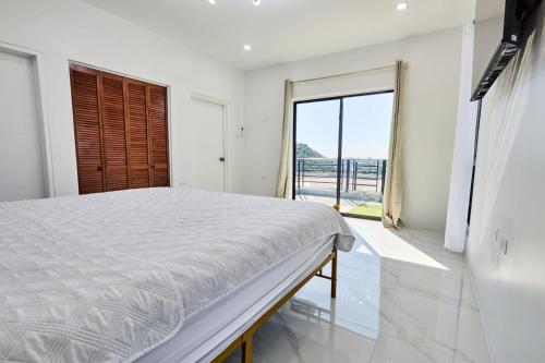 a white bedroom with a bed and a large window at Sunset Havendale in Kingston