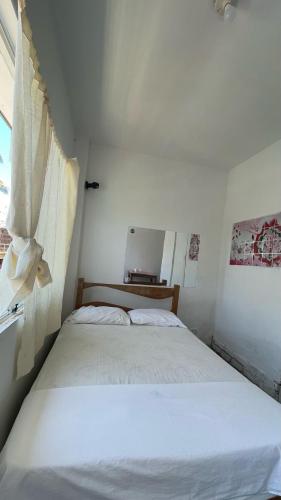 a white bed in a room with a window at Hostel Angeles del Mar in San Antonio