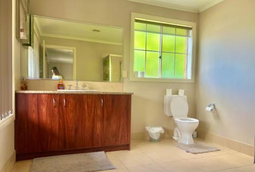 a bathroom with a sink and a toilet with a mirror at Golf View Charm in Craigieburn