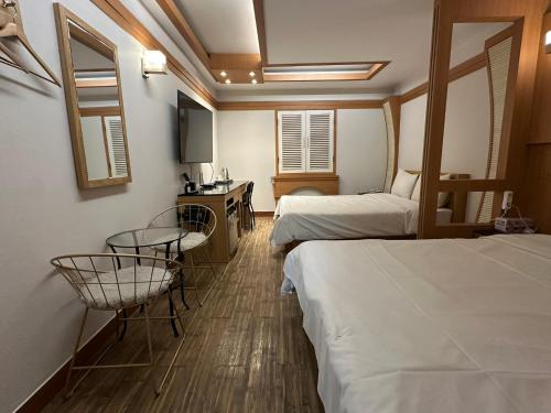 a hotel room with two beds and a table and chairs at 평촌코아 in Mabun-ni