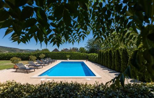 a swimming pool in a yard with chairs and trees at Holiday house Anetta with 5 bedrooms in Imotski